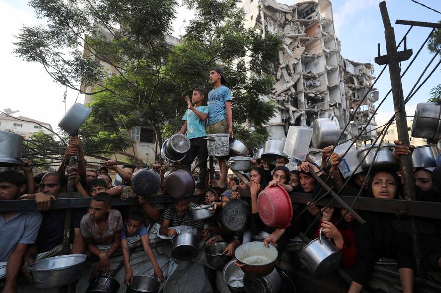 Palestinians wait to receive food from a charity kitchen, amid a hunger crisis, in Gaza City