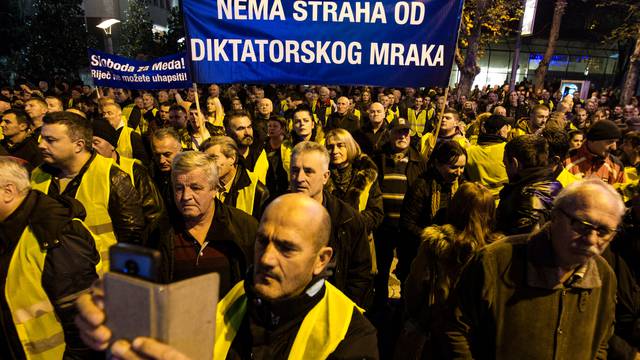 Protesters wearing yellow vests hold a banner during a protest against the arrest of Nebojsa Medojevic in Podgorica