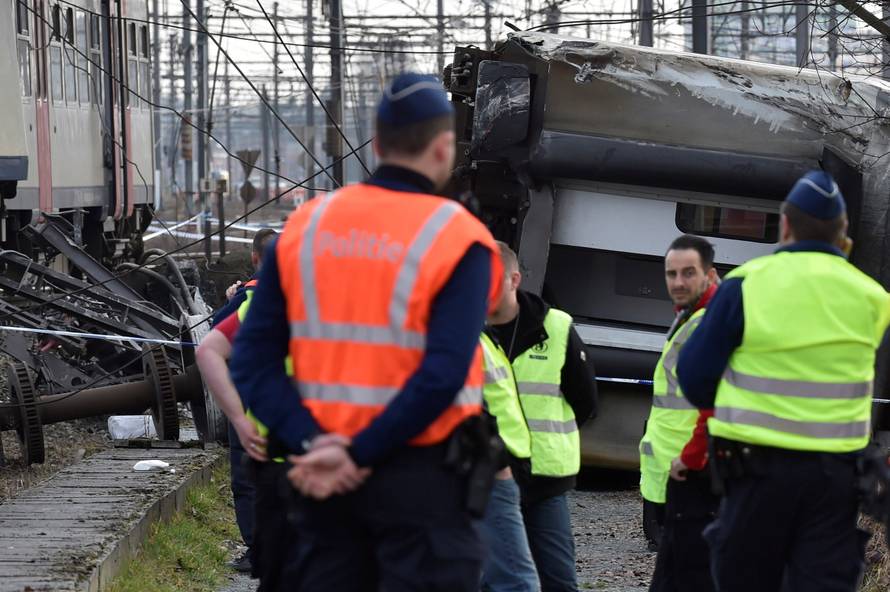 Rescuers and police officers stand next to the wreckage of a passenger train after it derailed in Kessel-Lo near Leuven
