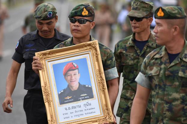 An honour guard hold up a picture of Samarn Poonan, 38, a former member of Thailand