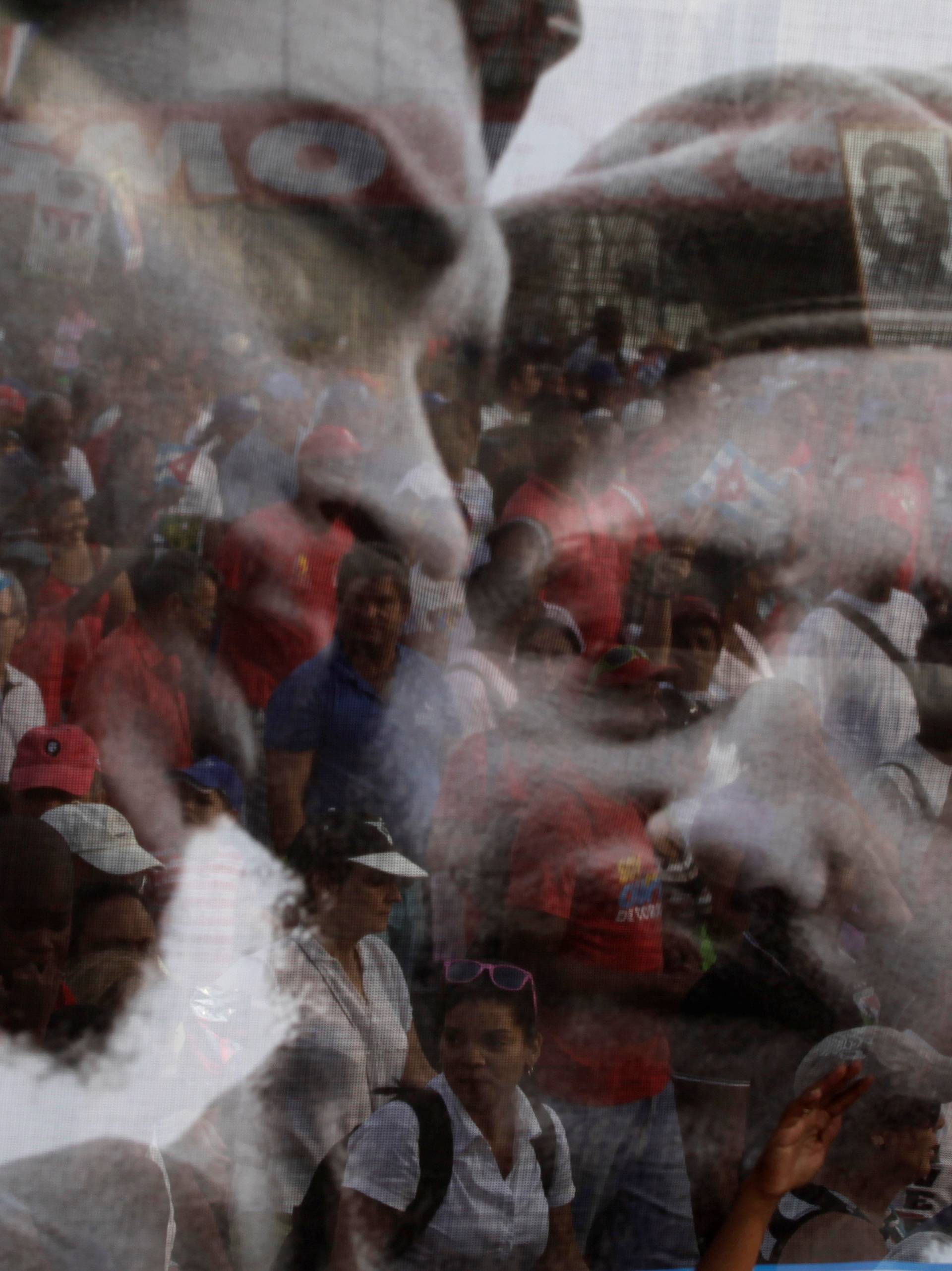 File photo of people being seen through a poster with a picture of Cuba's former leader Fidel Castro and late Argentine revolution leader Che Guevara during the May Day parade in Havana's Revolution Square