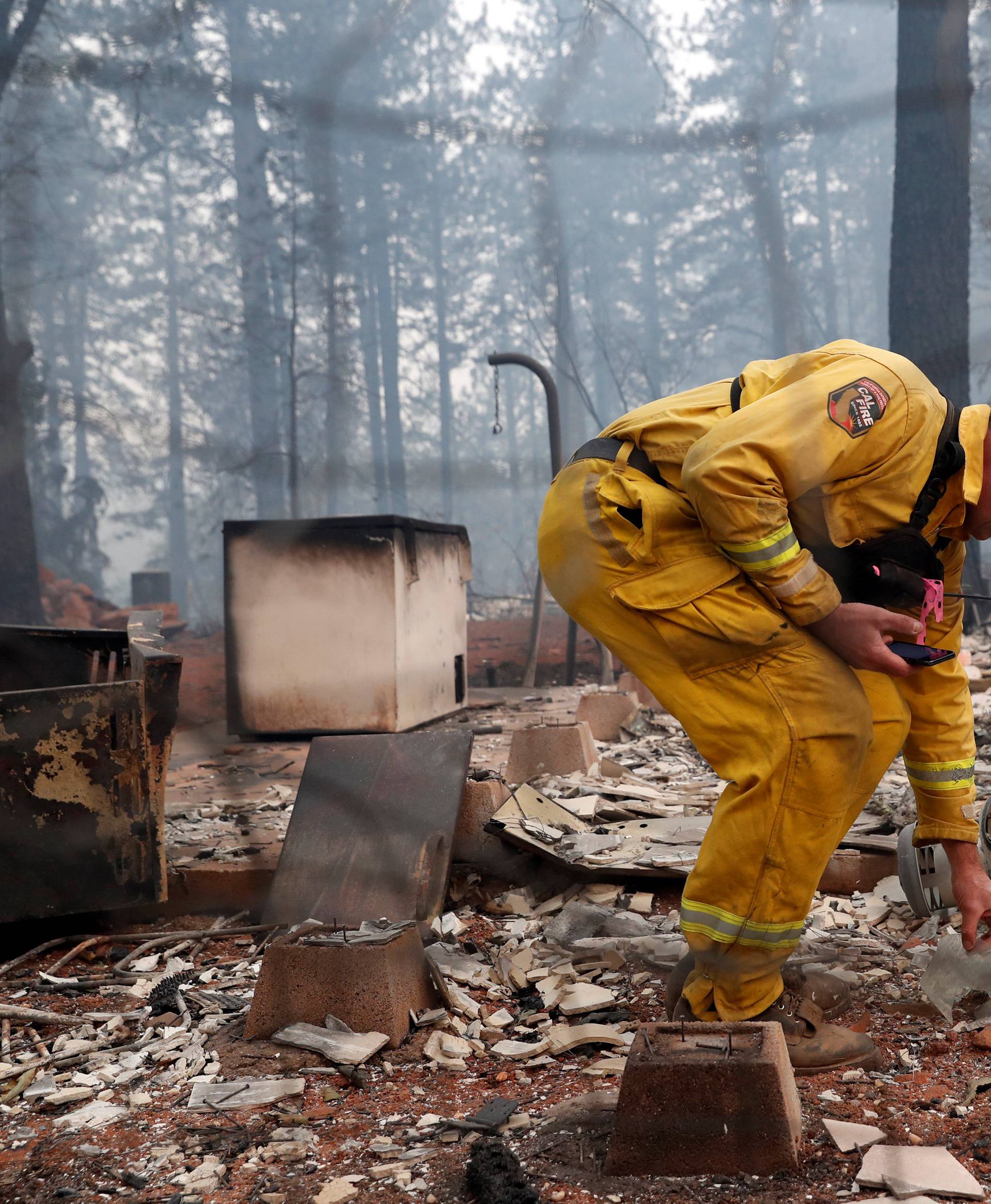 Cal Fire firefighter Stewart Morrow inspects a house destroyed by the Camp Fire in Paradise