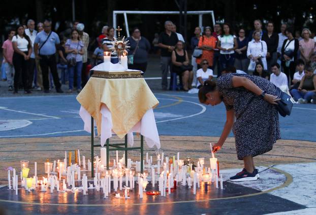 A woman light candles as she takes part in a candle vigil outside a church to pray for victims of earthquakes, in Valencia