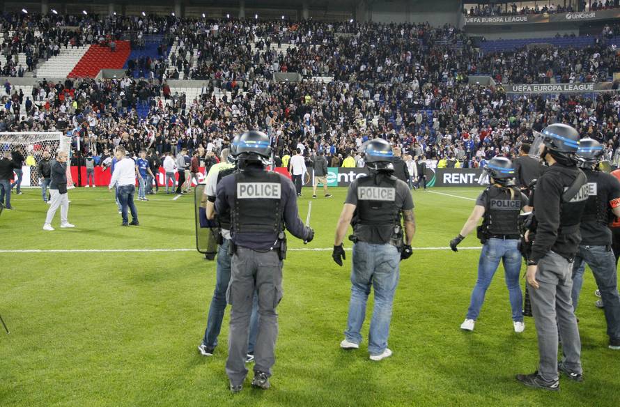 Police officers as Lyon fans invade the pitch and fans clash in the stands