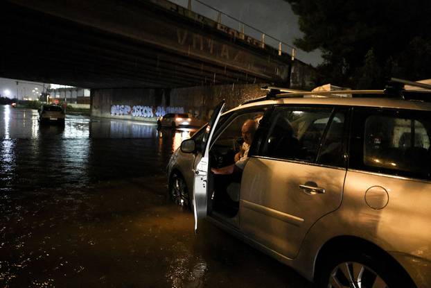 Demetrio, 75, sits inside his car while waiting for a tow truck after the vehicle became submerged in floodwater, on the outskirts of Barcelona