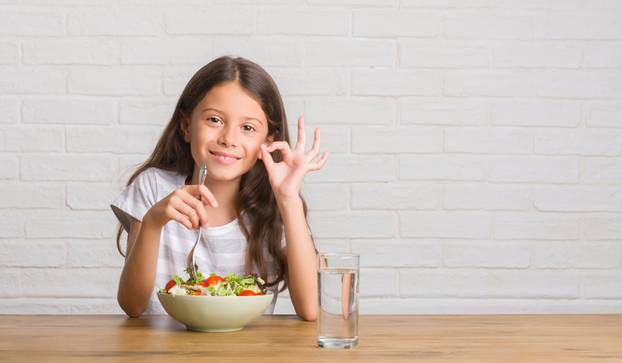 Young,Hispanic,Kid,Sitting,On,The,Table,Eating,Healthy,Salad