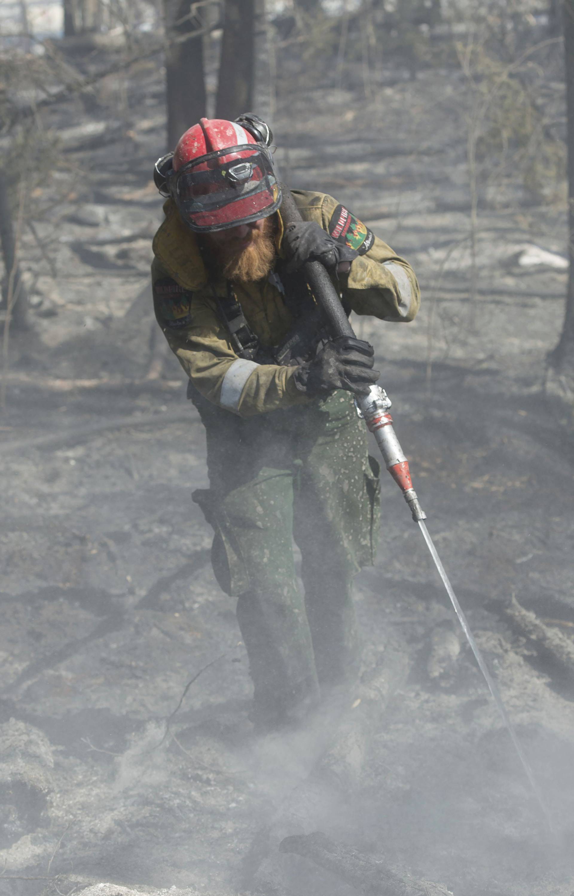 A member of Wildfire Management Alberta's Wild Mountain Unit out of Hinton, hoses down hotspots in the Parsons Creek area of Fort McMurray