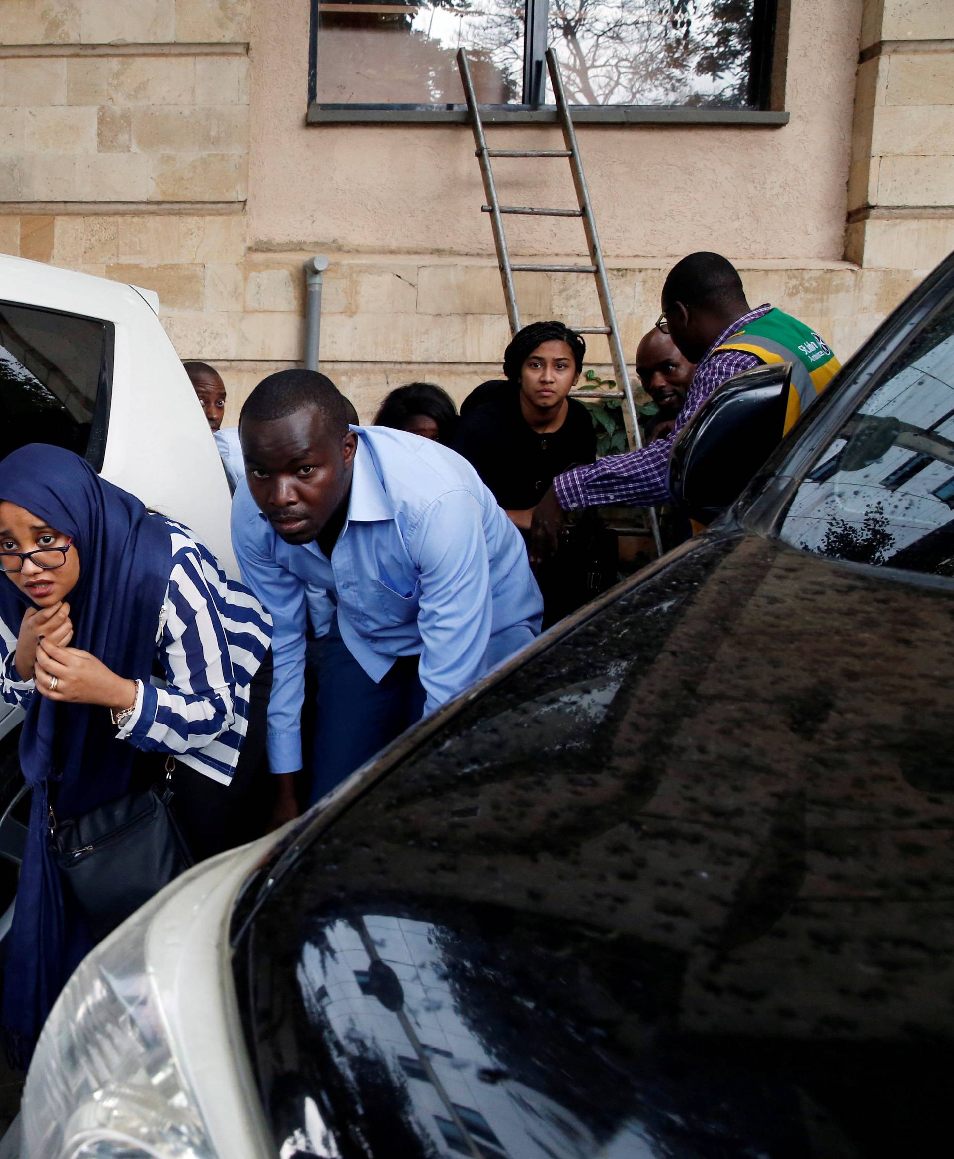 People are evacuated by a member of security forces at the scene where explosions and gunshots were heard at the Dusit hotel compound, in Nairobi