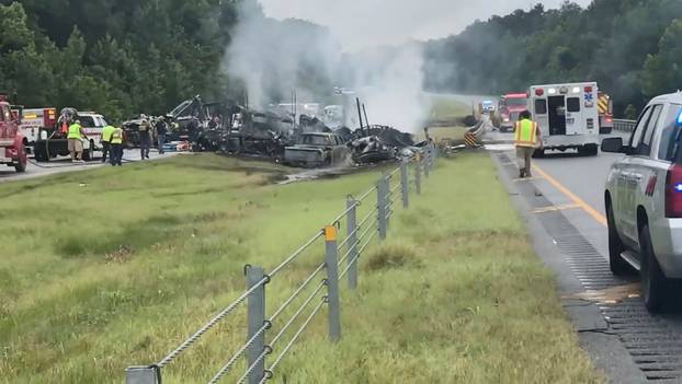 Emergency personnel work at the accident site as smoke rises from the wreckage after about 18 vehicles slammed together on a rain-drenched Alabama highway during Tropical Storm Claudette, in Butler County, Alabama