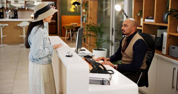 Hotel, receptionist and woman at front desk talking for booking, accommodation and reservation. Hospitality, travel and person with concierge for guest room, lodge and check in service in lobby