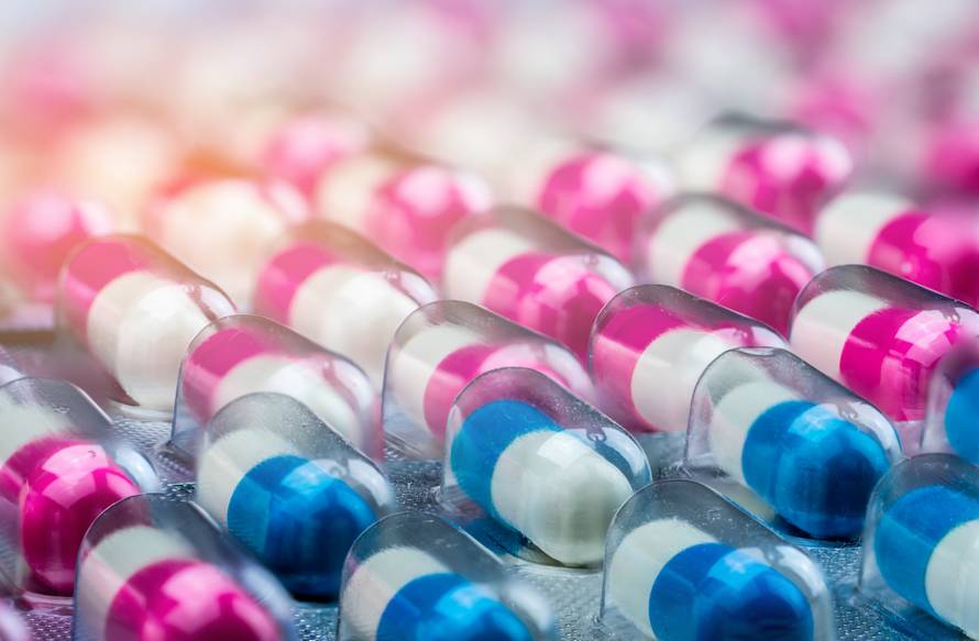 Closeup pink-white and blue-white antibiotics capsule pills in b