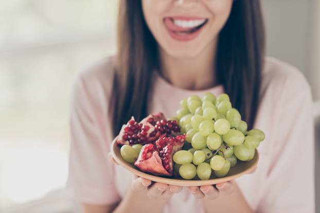 Cropped close-up portrait of her she nice attractive pretty charming cheerful cheery brown-haired single girl sitting on sofa licking lip eating tasty berries staying home apartment