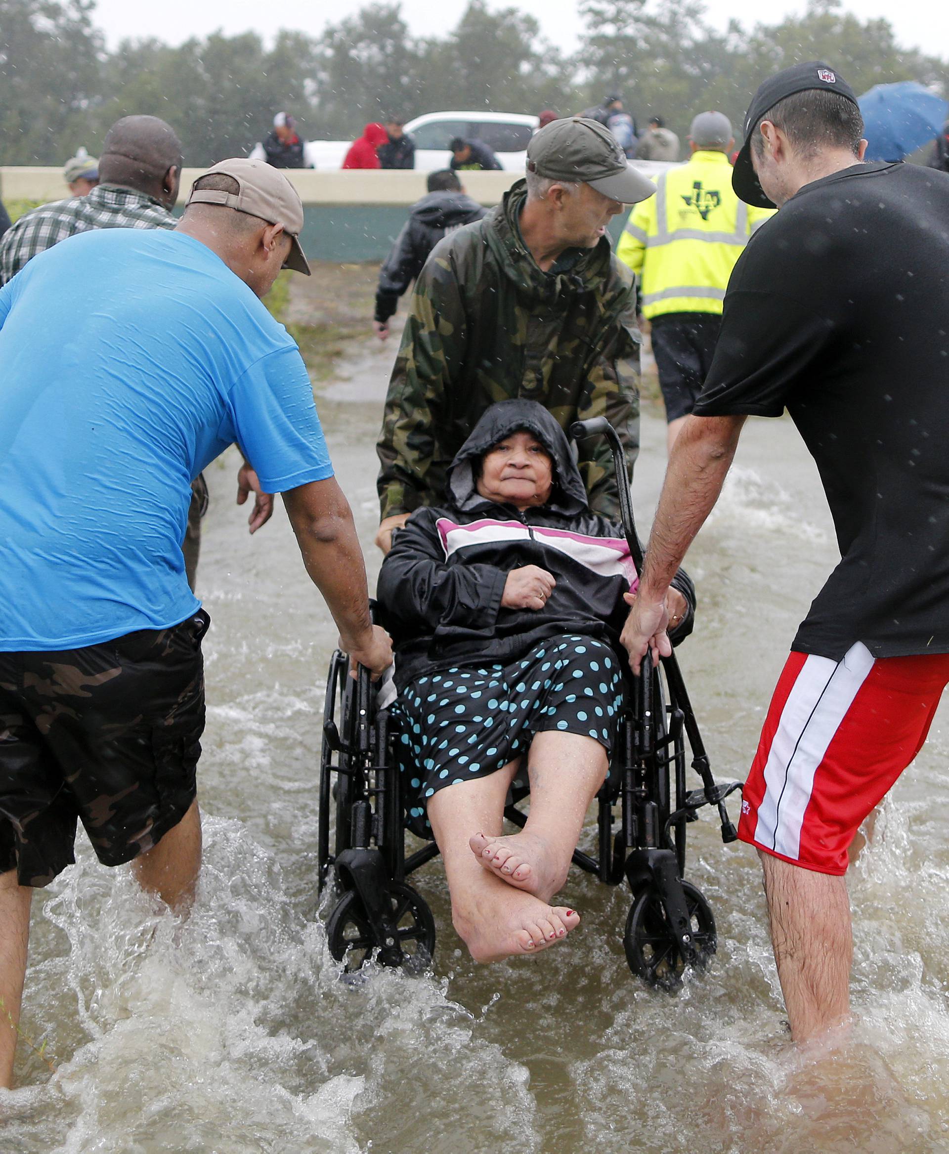 An elderly woman in a wheelchair is rescued from the flood waters of tropical storm Harvey in east Houston