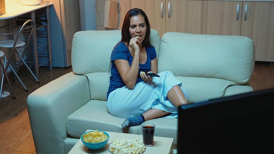 Woman Holding Remote Control And Eating Popcorn Relaxing On Couc