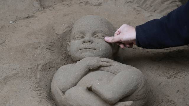 An artist works on a sand sculpture representing baby Jesus as a part of nativity scene in St. Peter's square at the Vatican