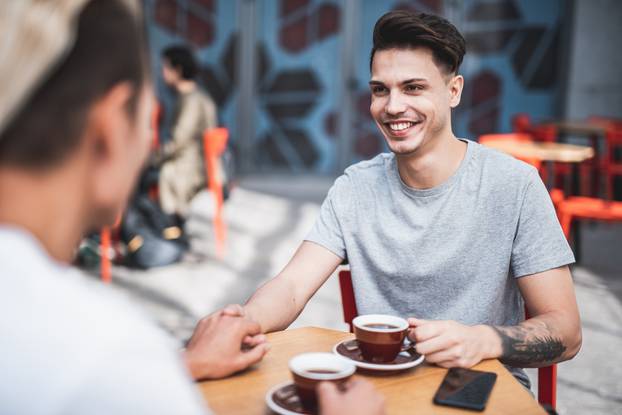 Positive male drinking mugs of coffee together