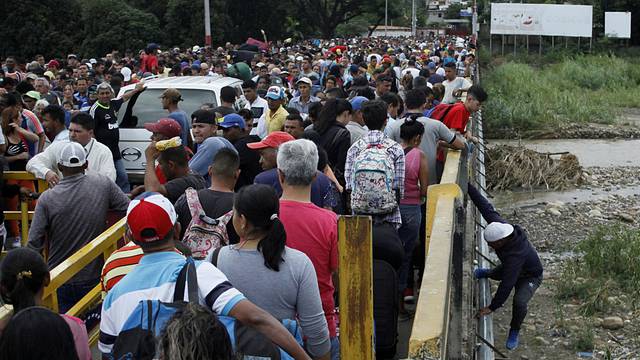 FILE PHOTO: A man gets off the bridge as people queue to try to cross the Venezuela-Colombia border through Simon Bolivar international bridge in San Antonio del Tachira