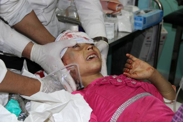 Medics attend to a girl injured by a Saudi rocket attack on the border area of Razeh of Yemen