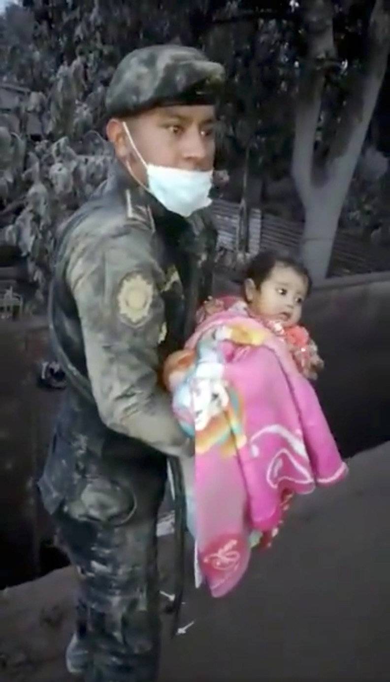 A soldier rescues a girl from a hole in an area affected by the eruption of Fuego volcano in Escuintla