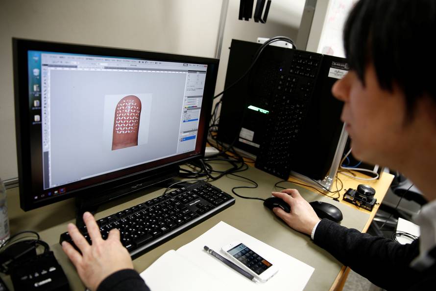 Researcher Ogane works to analyse Echizen' fingerprint covered with a home-made biometric jammer during a demonstration of their experiment for Reuters in Tokyo