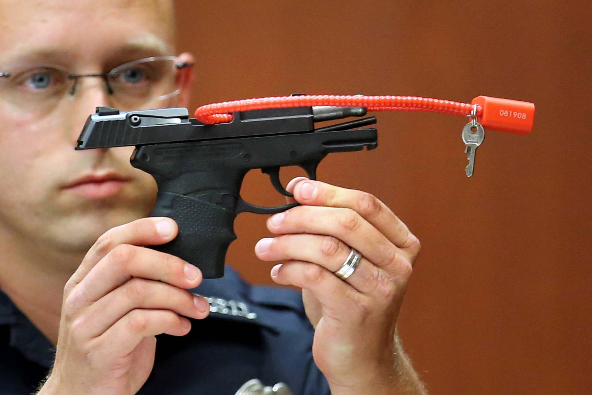 Sanford police officer Timothy Smith holds up the gun that was used to  kill Trayvon Martin, while testifying during George Zimmerman's murder trial in Seminole circuit court in Sanford