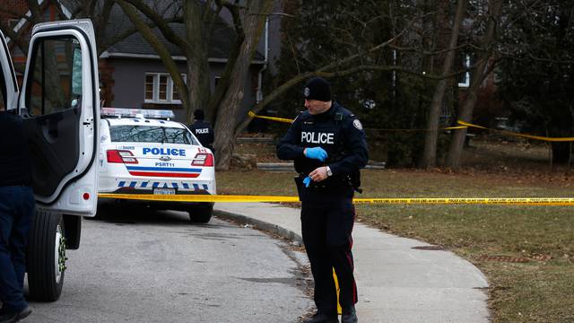 Police officers guard the grounds of a house they searched in Toronto