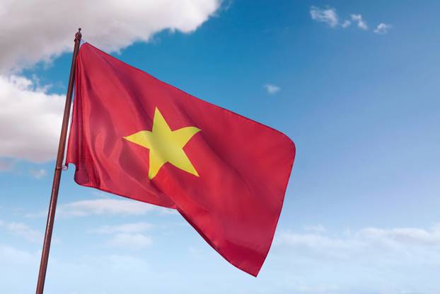 A red and yellow flag with a yellow star on it is flying in the sky