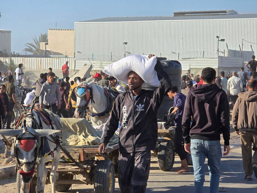 Palestinians gather at an aid distribution center in Deir Al-Balah, in the Gaza Strip