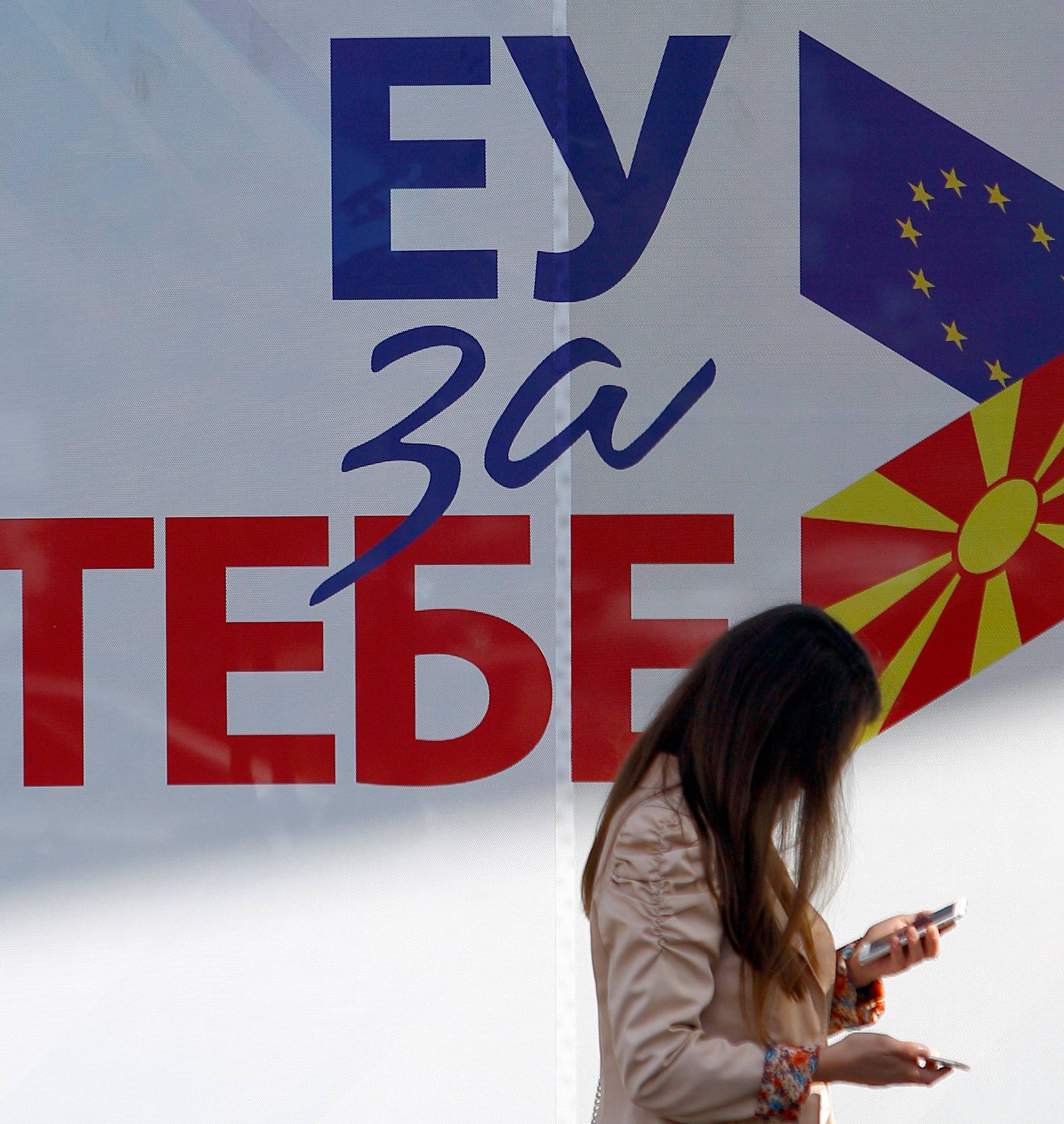 A woman passes next to posters reading "EU for you" for the referendum in Macedonia on changing the country's name in Skopje
