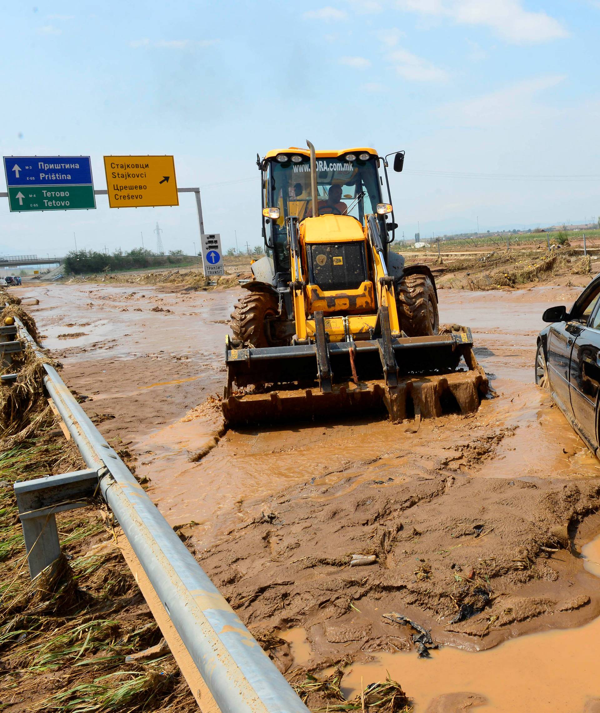 A man with tractor cleans the mud on the highway after heavy floods in Cento 