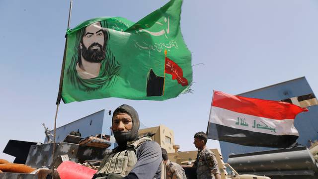 A Shi'ite fighter stands next to a religious flag near Falluja