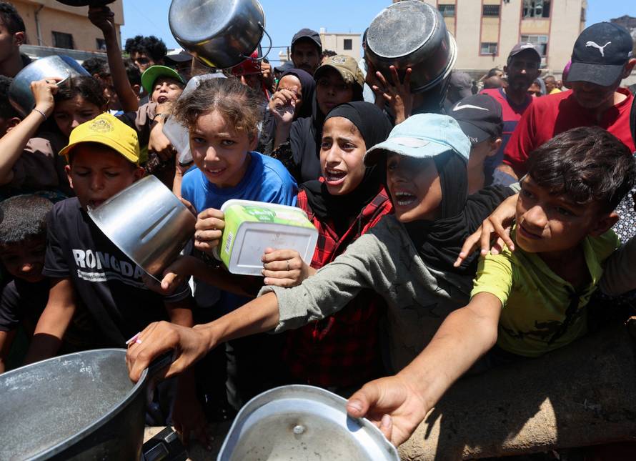 Palestinians gather to receive food from a charity kitchen, amid a hunger crisis, in Nuseirat