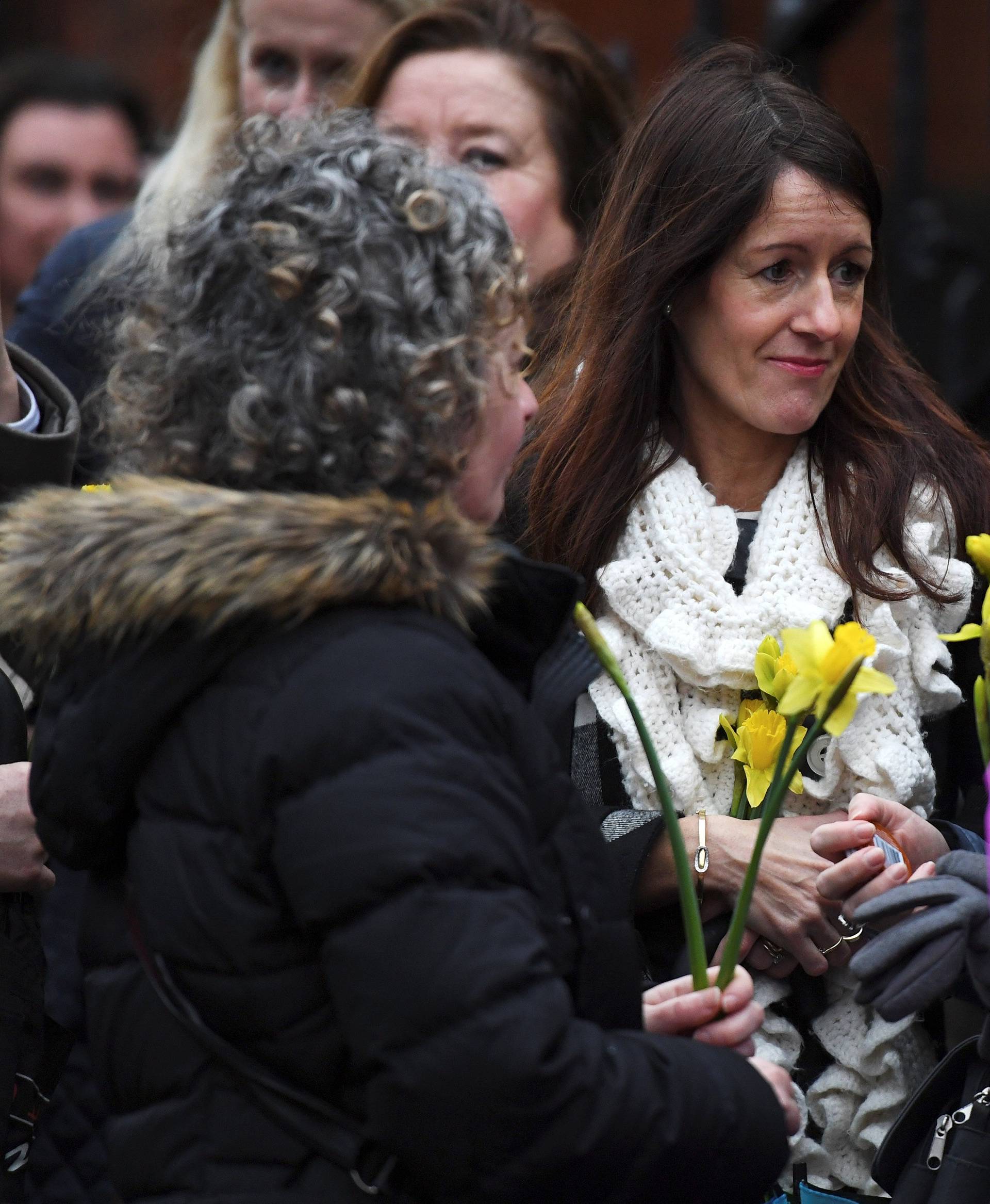 Schoolfriends bring yellow flowers to represent sunshine as they queue up to view Cranberries singer Dolores O'Riordan's coffin  as it is carried into St. Joseph's Church for a public reposal in Limerick