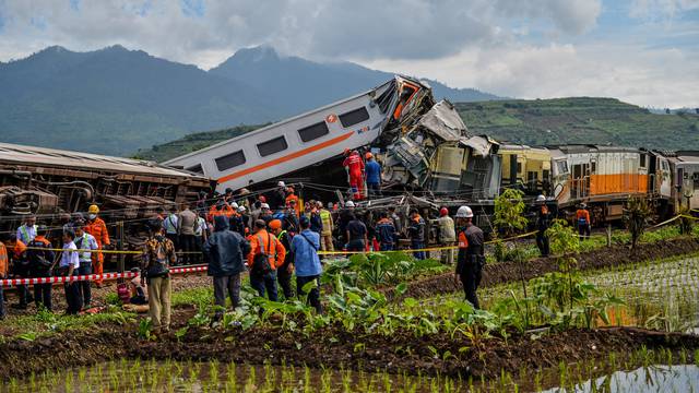 People stand at the site of a train collision between the local Bandung Raya train and the Turangga train in Cicalengka