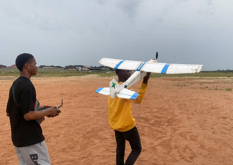 Chris Chinedu and Damilare Ajayi, friends of Bolaji Fatai, who built the model aeroplane from discarded waste, prepare to fly the model aeroplane, in Lagos