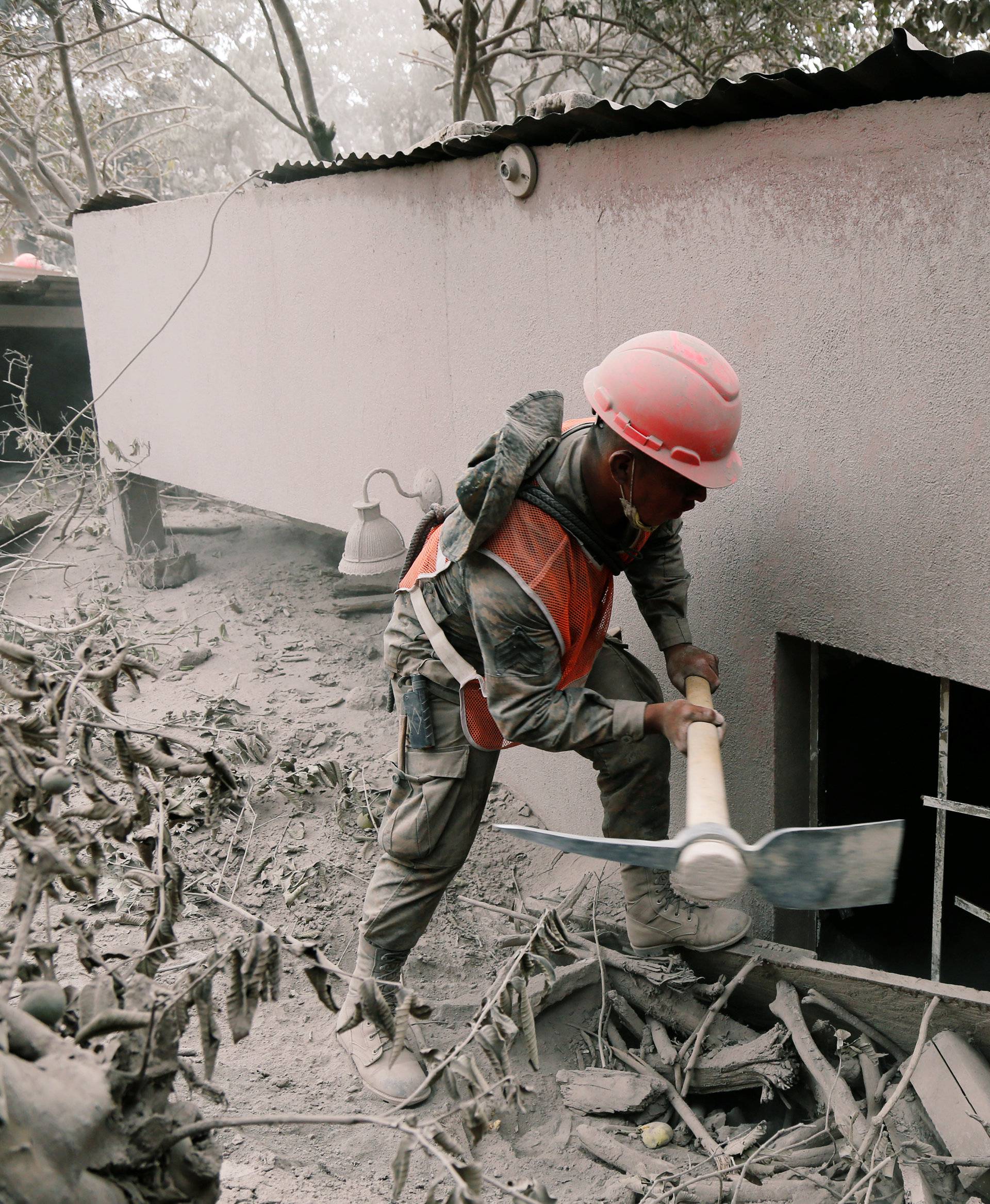A soldier uses a pick at an area affected by the eruption of the Fuego volcano in the community of San Miguel Los Lotes in Escuintla