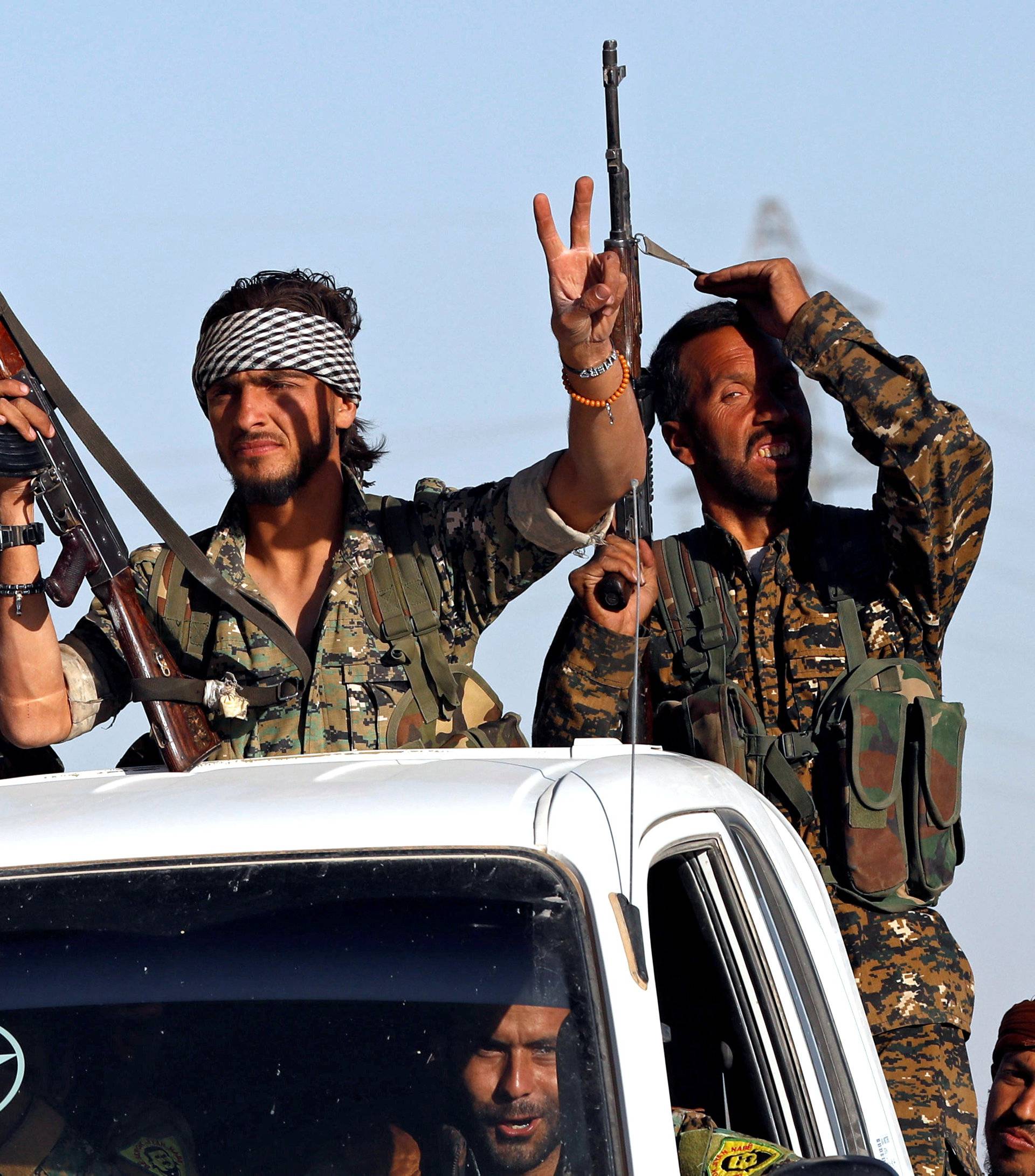 Fighters of Syrian Democratic Forces make the V-sign as their convoy passes in Ain Issa