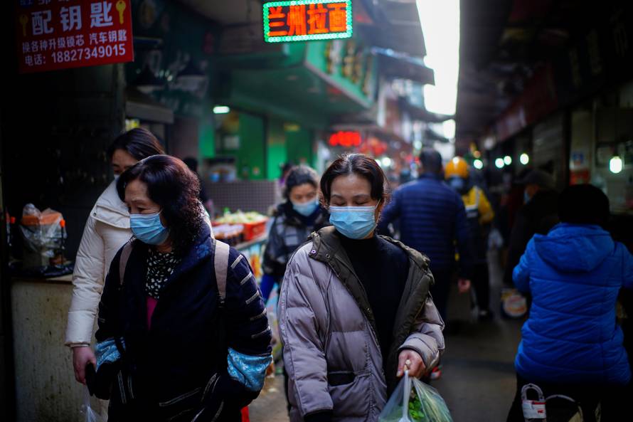 People wearing face masks walk on a street market, following an outbreak of the coronavirus disease (COVID-19) in Wuhan