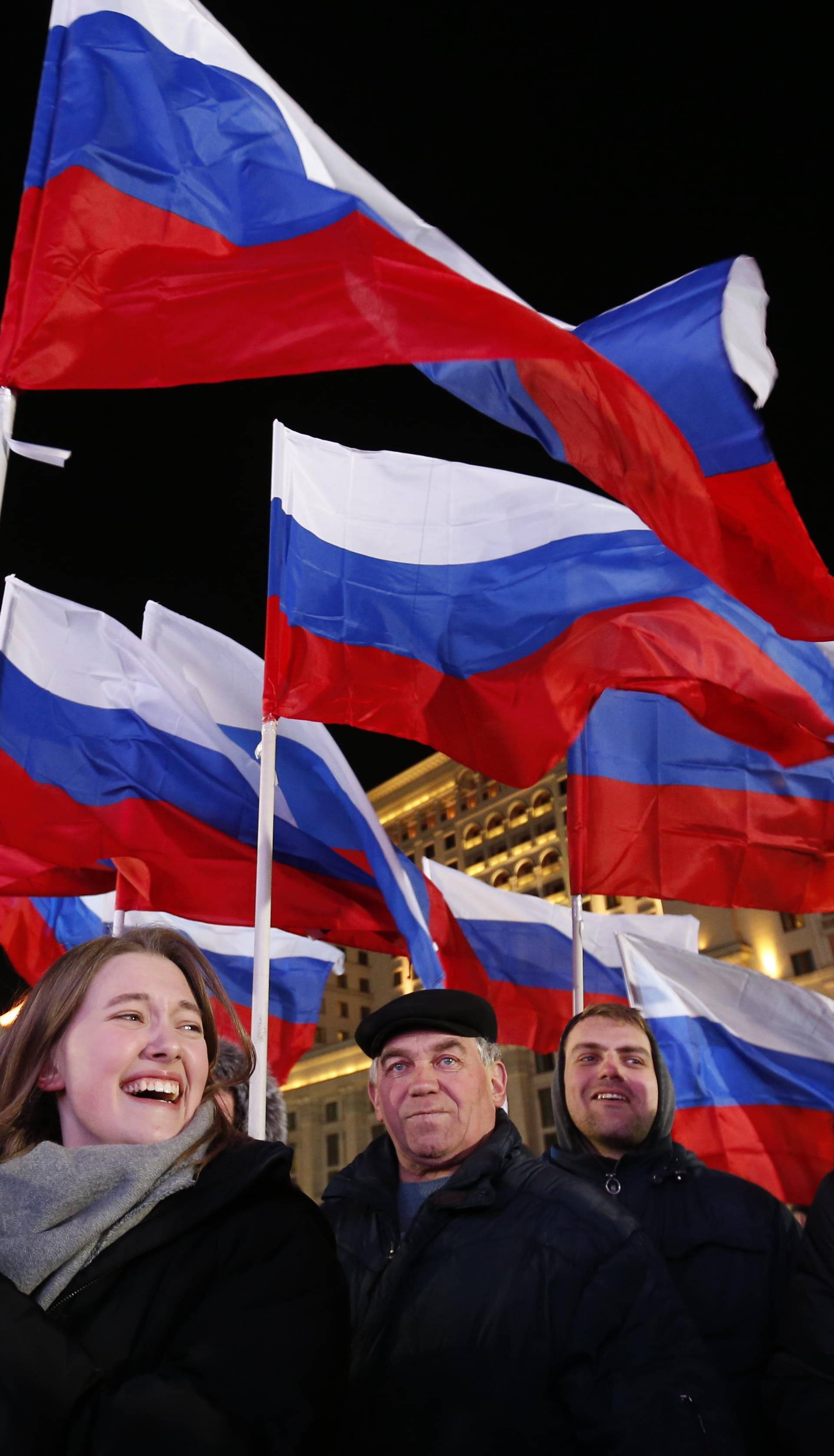 People wave Russian flags during a rally and concert marking the fourth anniversary of Russia's annexation of the Crimea region, at Manezhnaya Square in central Moscow