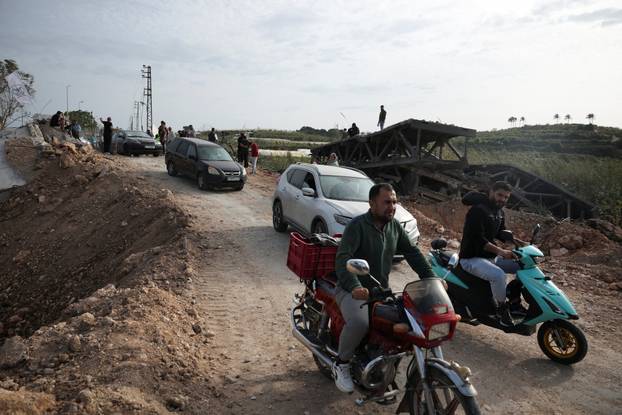 Displaced people cross the bridge linking southern Lebanon to the rest of the country, which was hit earlier in an Israeli strike, in Qasmiyeh