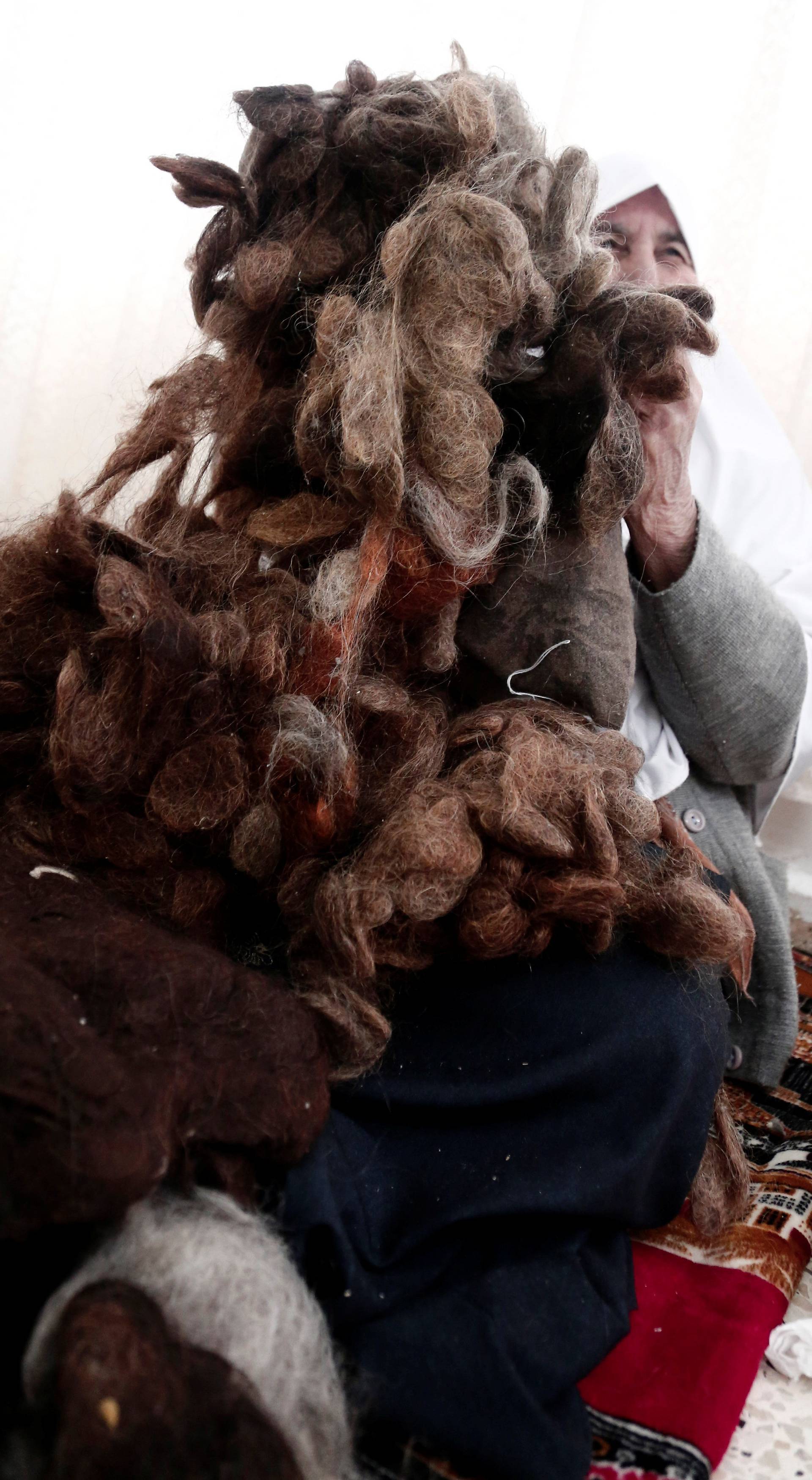 Ezzeya Daraghmeh, an 82-year-old Palestinian woman who said she has kept parts of her hair she cut over 67 years, holds her collected hair before stuffing it in a pillow, in the West Bank town of Tubas