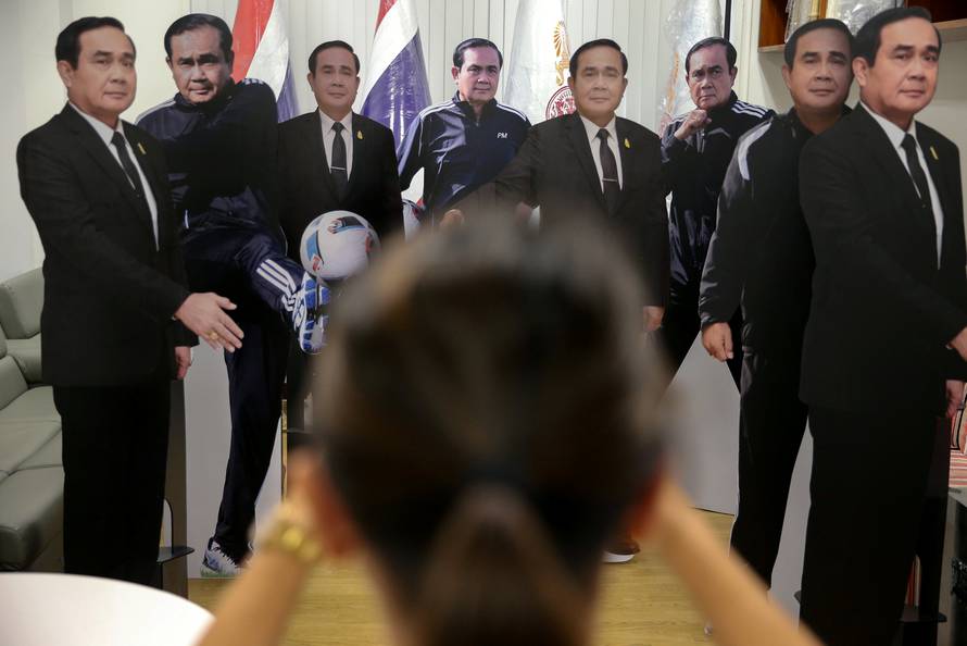 A journalist takes a photo of cardboard cut-outs of Thailand's Prime Minister Prayuth Chan-ocha at Government House in Bangkok