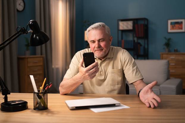 Older,Man,Laughs,Into,His,Phone,Webcam.,Elderly,Executive,Is