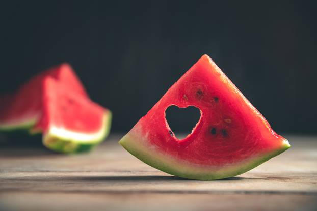 A cut piece of watermelon with a heart-shaped hole. Summer, joy, happiness, delicious food
