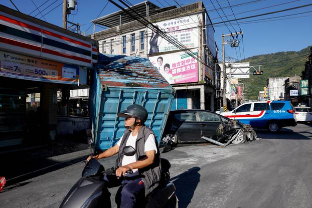 A man rides past a damaged convenience store, after flooding brought by Super Typhoon Ragasa, in Hualien