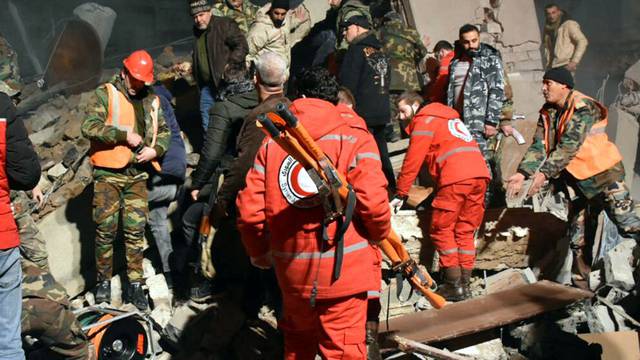 Rescuers search for survivors under the rubble of a damaged building in Homs province