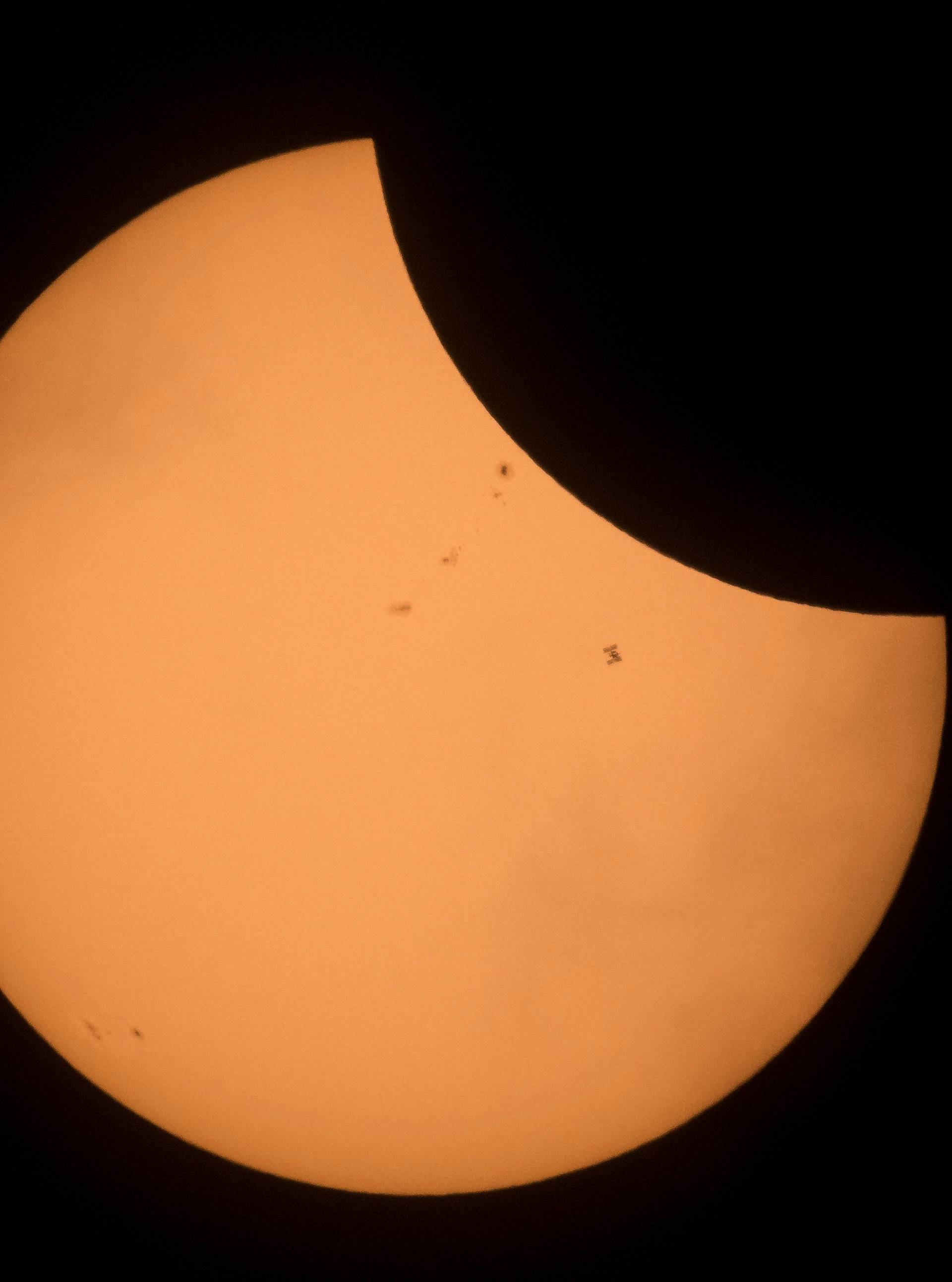 The International Space Station is seen in silhouette as it transits the sun during a partial solar eclipse seen near Banner Wyoming