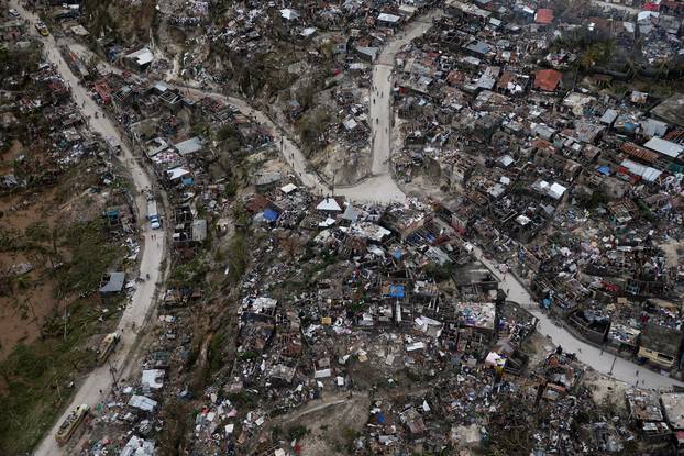 People walk down the streets next to destroyed houses after Hurricane Matthew passes Jeremie, Haiti