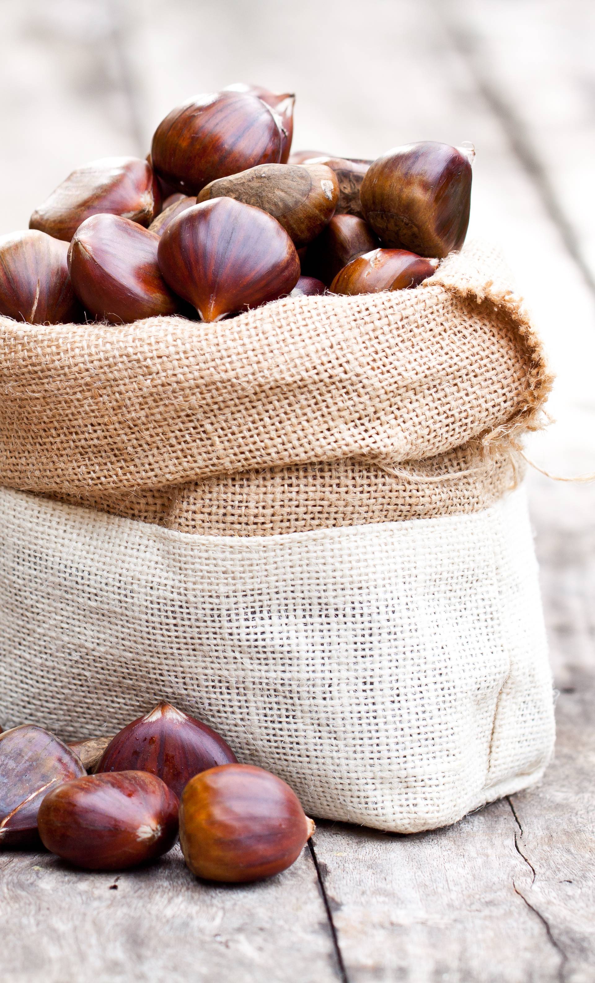 fresh  chestnuts in sack bag on the old wooden table