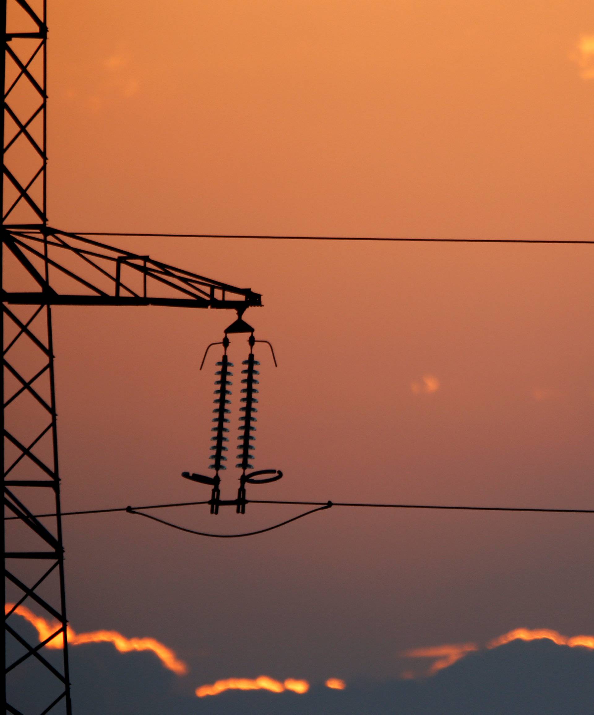 Electrical power pylons of high-tension electricity power lines are seen at sunset in Cambligneul